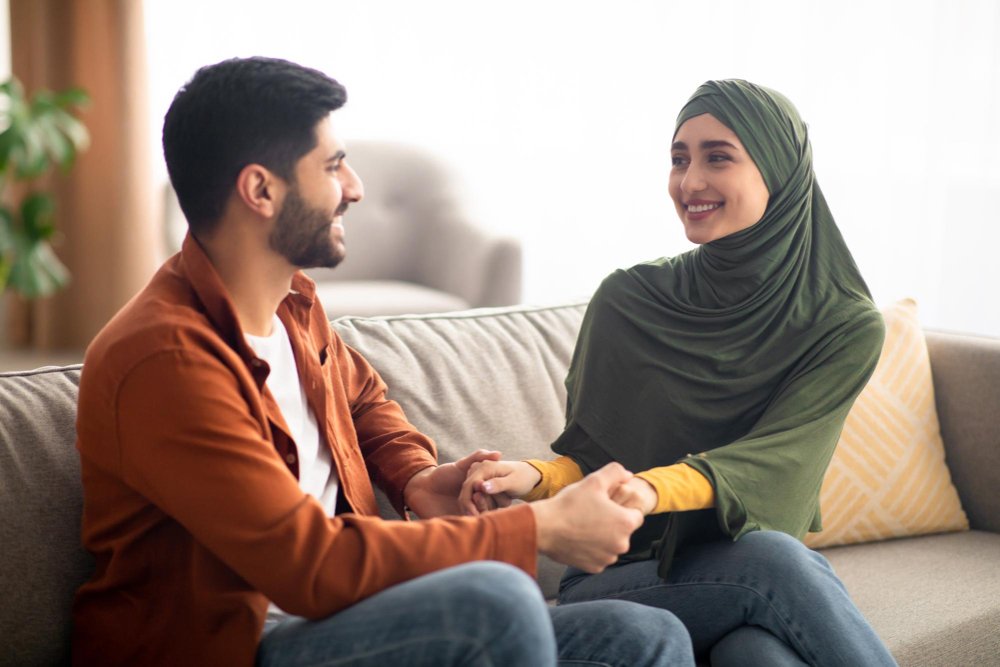 happy-middle-eastern-couple-holding-hands-sitting-home happy-middle-eastern-couple-holding-hands-sitting-home